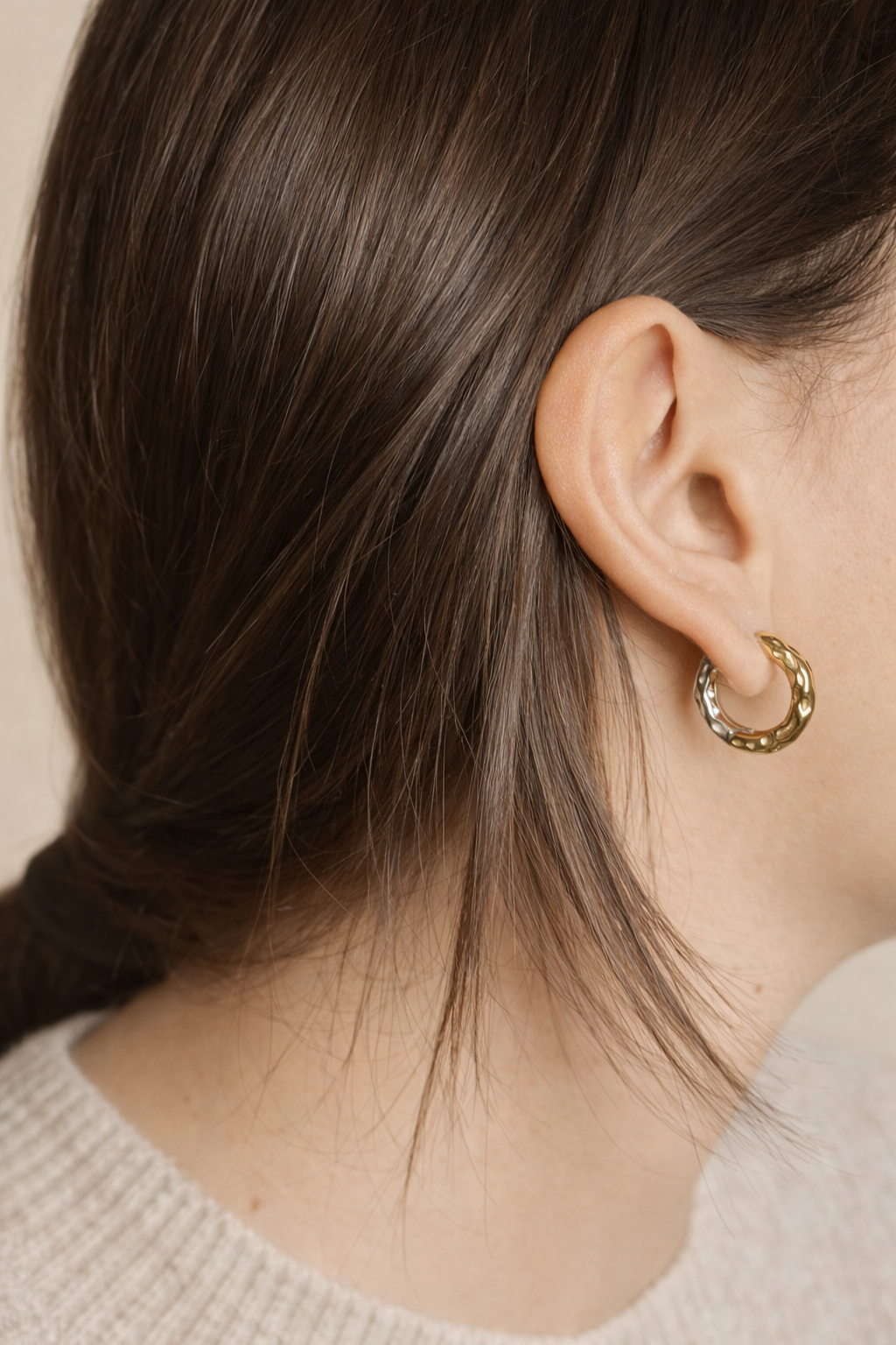 Woman wearing LUMHARA 18K gold-plated textured hoop earring, close-up view