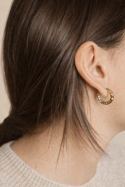Woman wearing LUMHARA 18K gold-plated textured hoop earring, close-up view