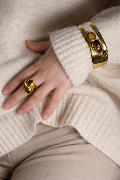 Hand wearing LUMHARA 18K gold plated ring and bracelet with natural stones on cream sweater