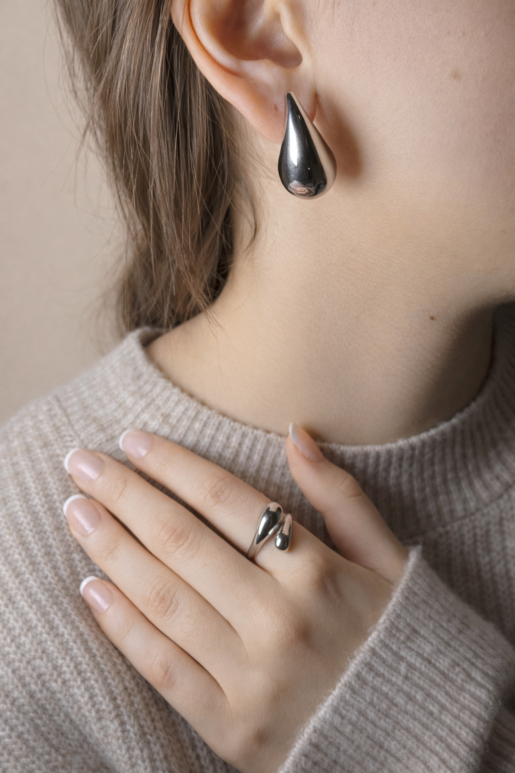 Close-up of woman wearing teardrop silver earring and matching silver ring by LUMHARA