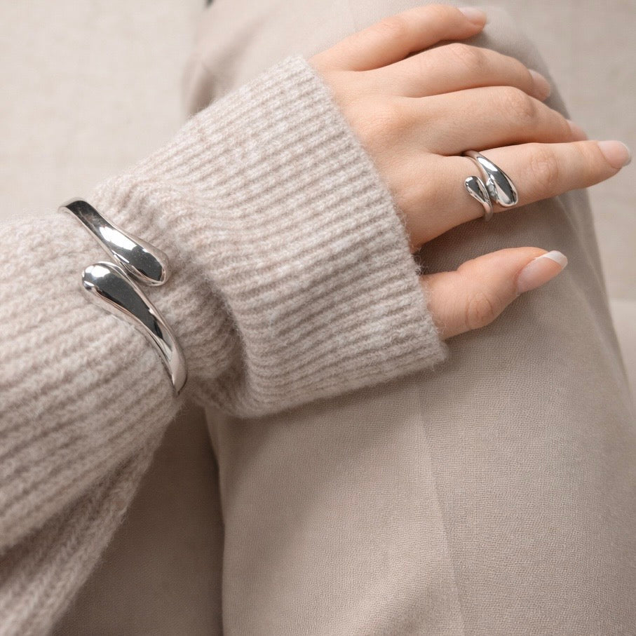 Woman wearing LUMHARA silver jewelry bracelet and ring on beige knit sweater