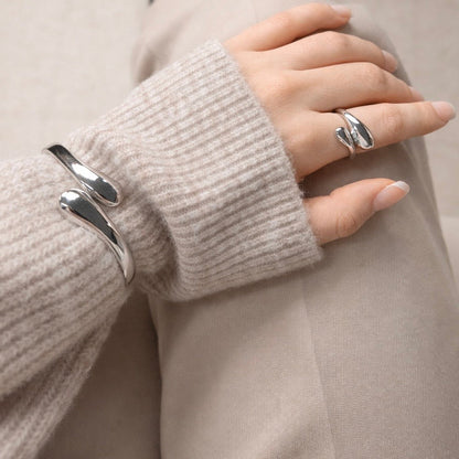 Woman wearing LUMHARA silver jewelry bracelet and ring on beige knit sweater